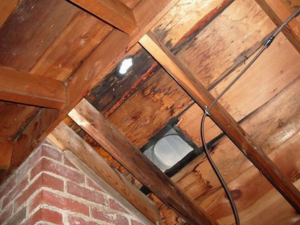 Wet roof boards in an attic, a common issue identified by roofing contractors in Lewes, indicating potential roof damage.