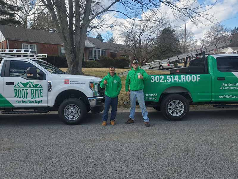 Rob and Lorens standing next to their work pickups and giving a thumbs-up to the camera