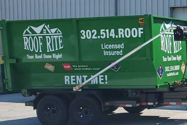Close up of a green Roof Rite dumpster for rent