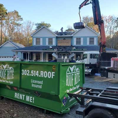 Roof Rite green dumpster at a residential roof job site