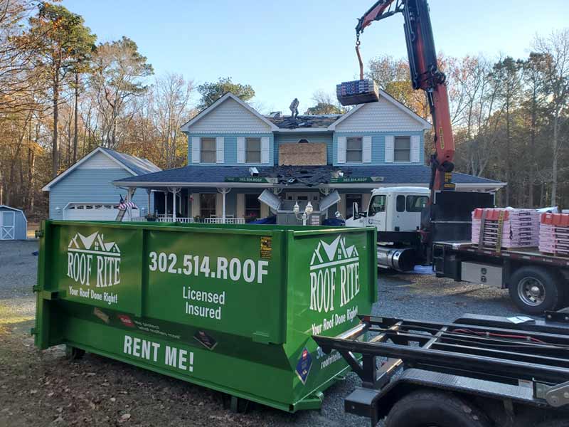 Roof Rite green dumpster at a residential roof job site