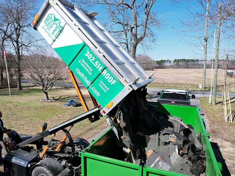 Roof Rite's Equipter dumping old shingles recently removed from a residential roof into a dumpster