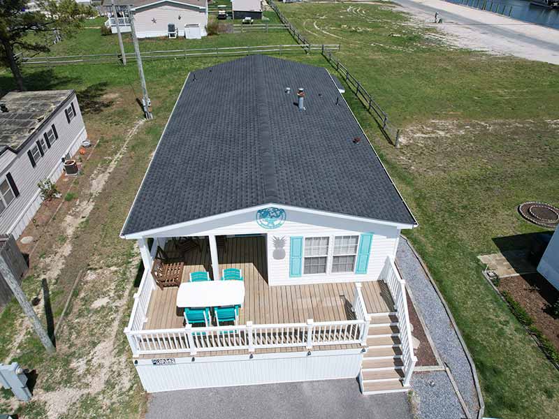 Top view of a small home with a porch and new dark gray shingles on its roof installed by Roof Rite